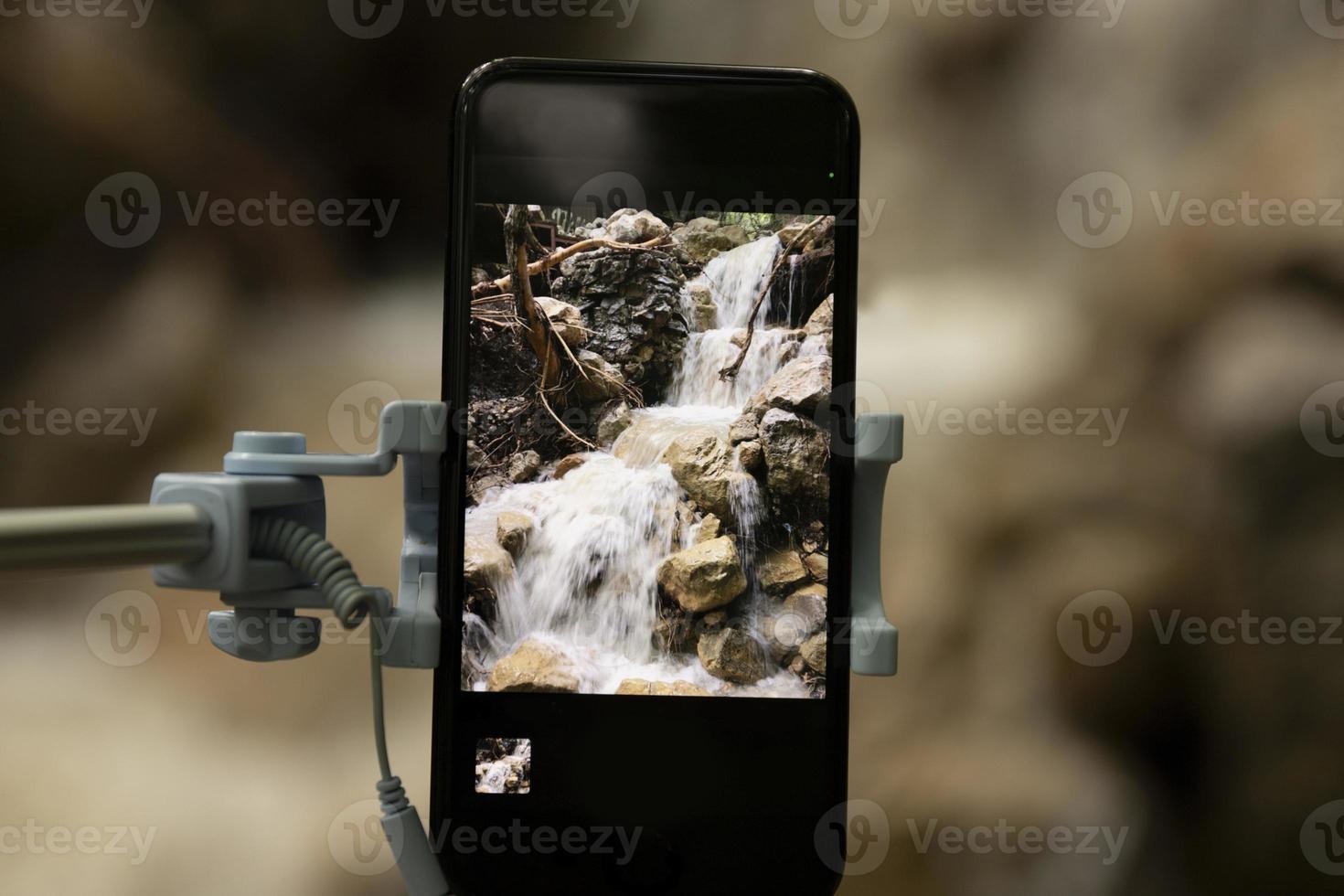 Taking pictures using a smartphone with a selfie stick on a blurred beautiful background. Close-up. photo