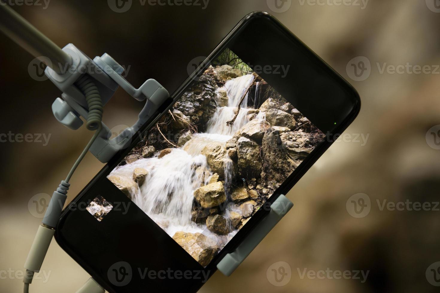 Taking pictures using a smartphone with a selfie stick on a blurred beautiful background. Close-up. photo