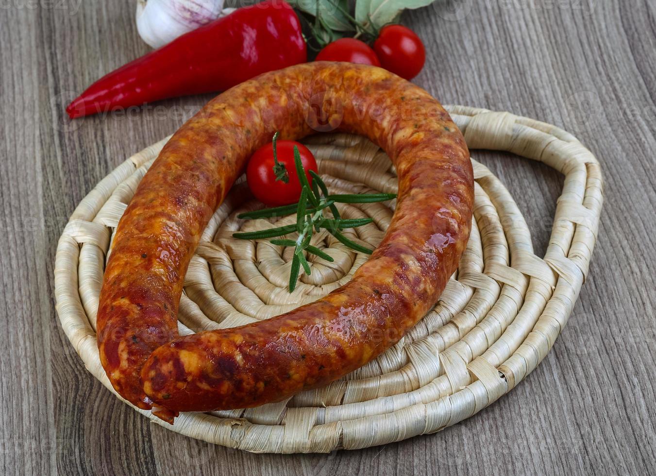 Sausage ring on wooden plate and wooden background photo