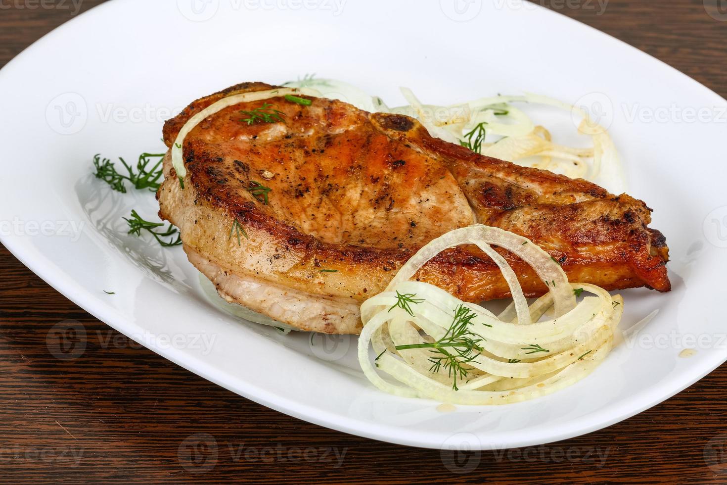 Grilled pork on the plate and wooden background photo