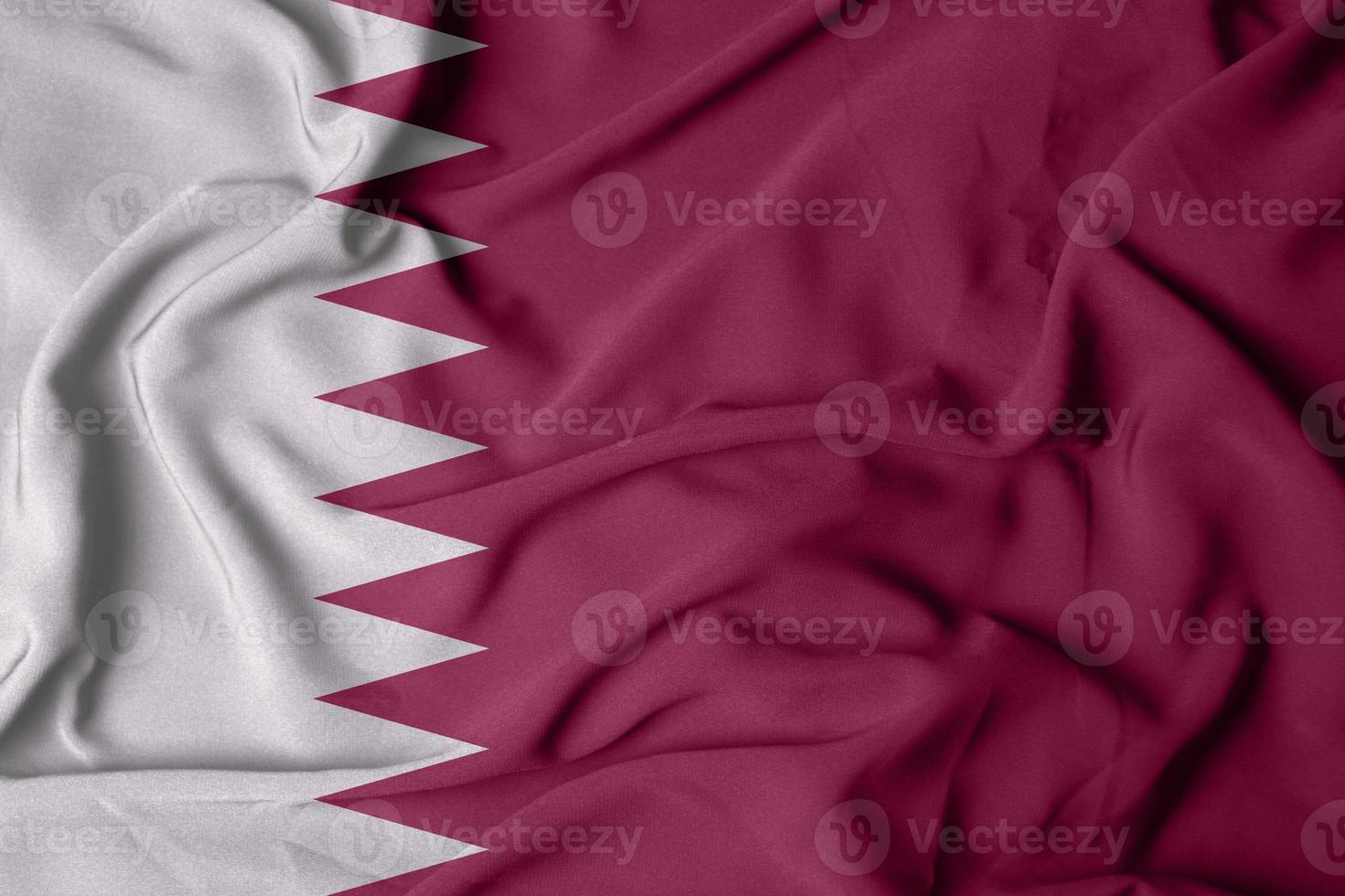 selective focus of Qatar flag, with waving fabric texture in burgundy color photo