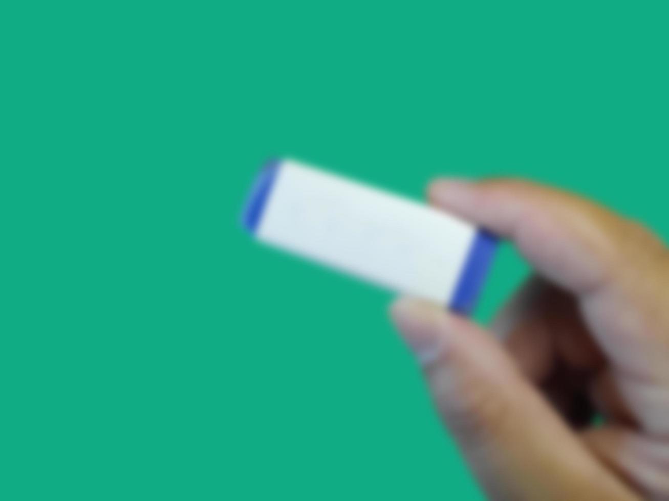 Abstract blurred of Hand holding eraser on green background photo