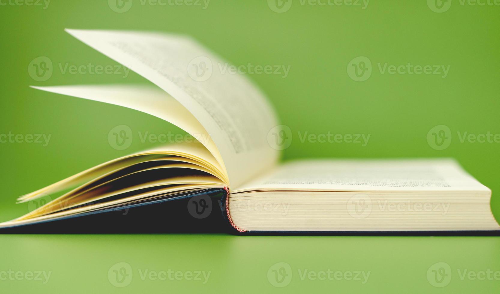 Thick book open and ready to read. on a green background The concept of learning education with open books or textbooks, stacks of literature, texts, academic documents. photo