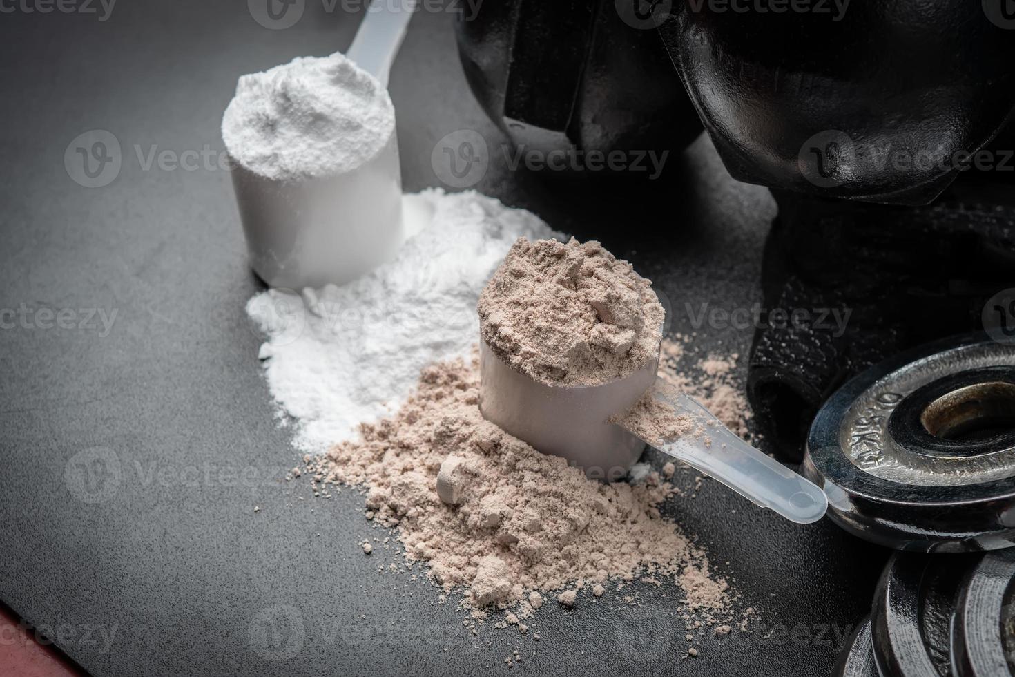 Scoop of protein powder and dumbbell background,Sports supplement,Fitness or healthy lifestyle concept. selective focus photo