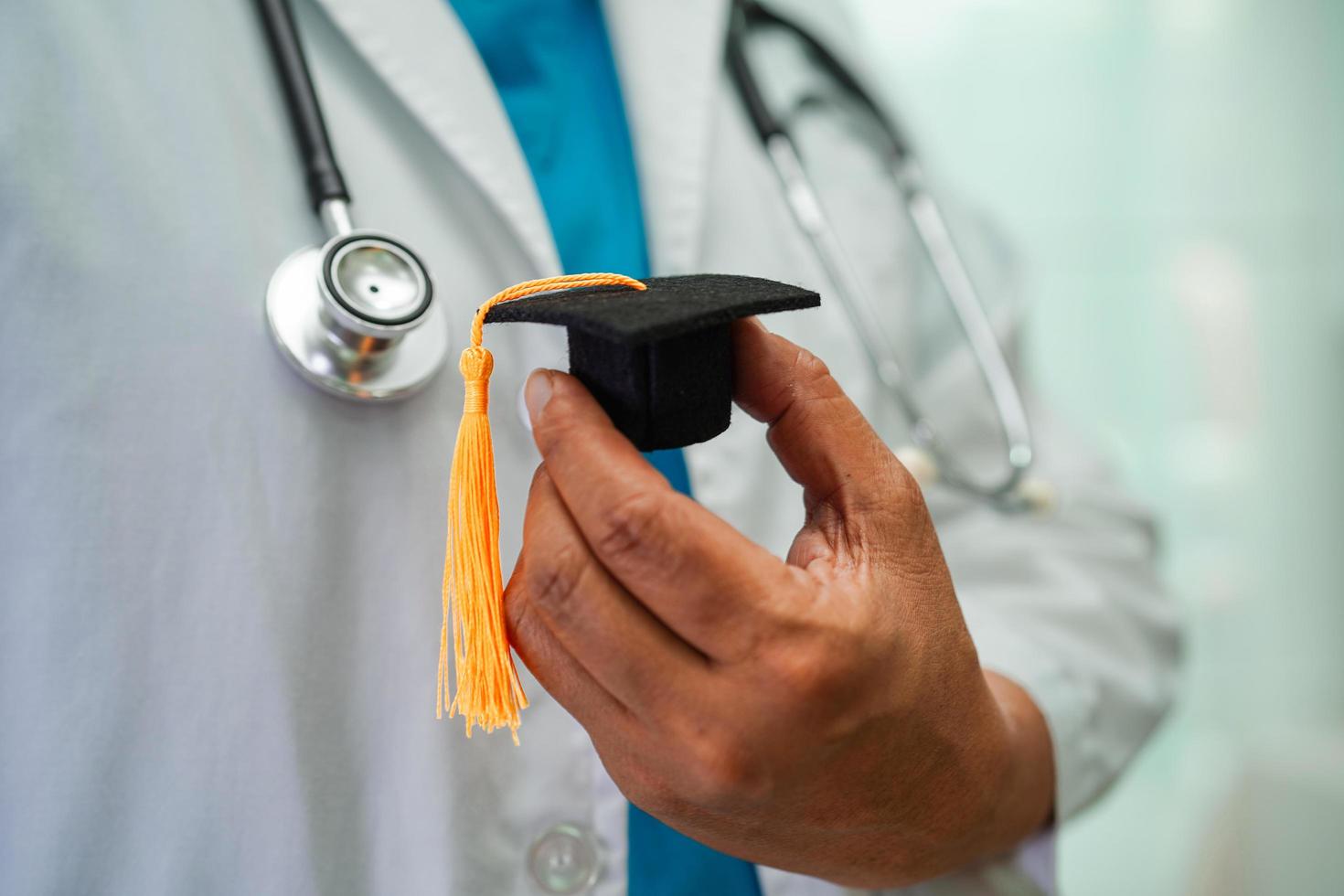 Asian woman doctor holding graduation hat in hospital, Medical education concept. photo