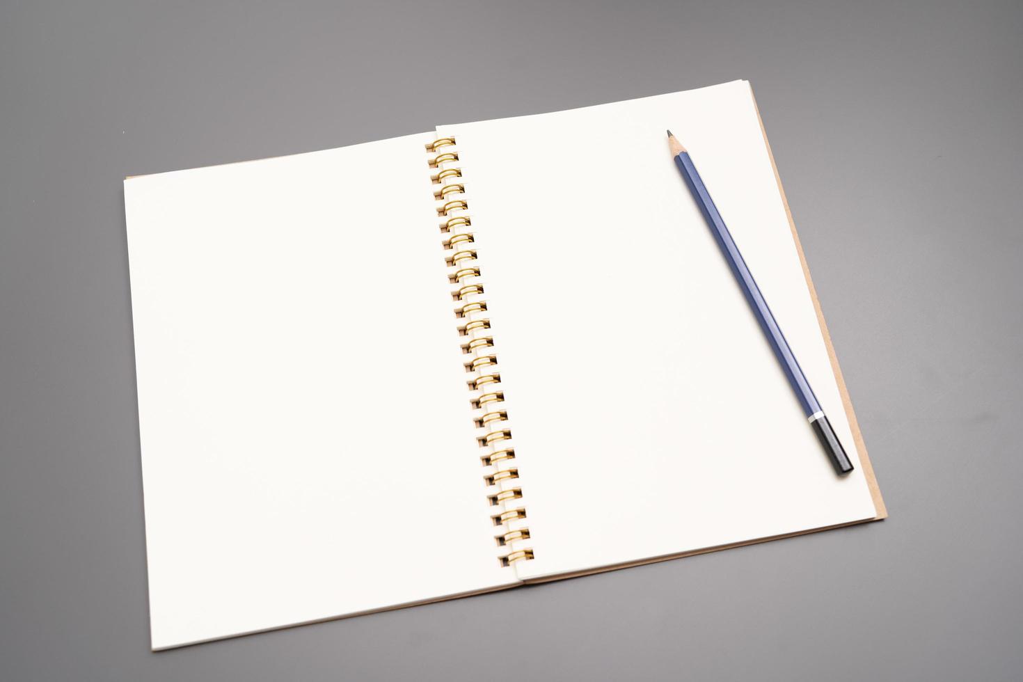 cuaderno con un lápiz. cuaderno espiral abierto en blanco con lápiz sobre fondo de escritorio blanco foto
