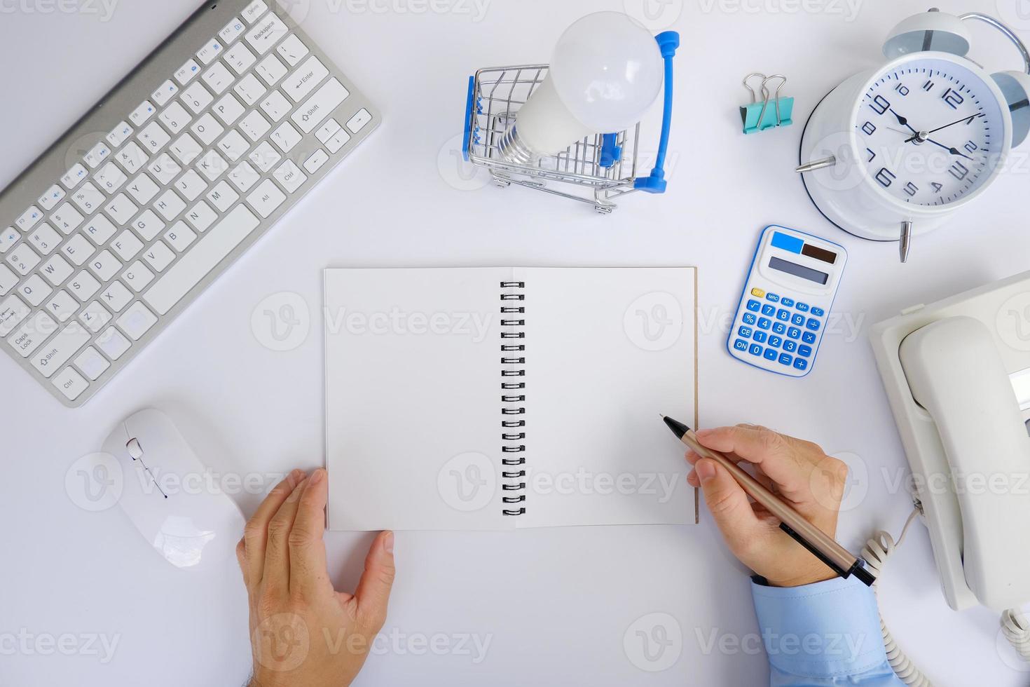 Office desk with smartphone, laptop computer, cup of coffee, and office tools. Flat lay, top view with copy space. A bank notepad and a pen are on top of an office desk table containing computer tools photo