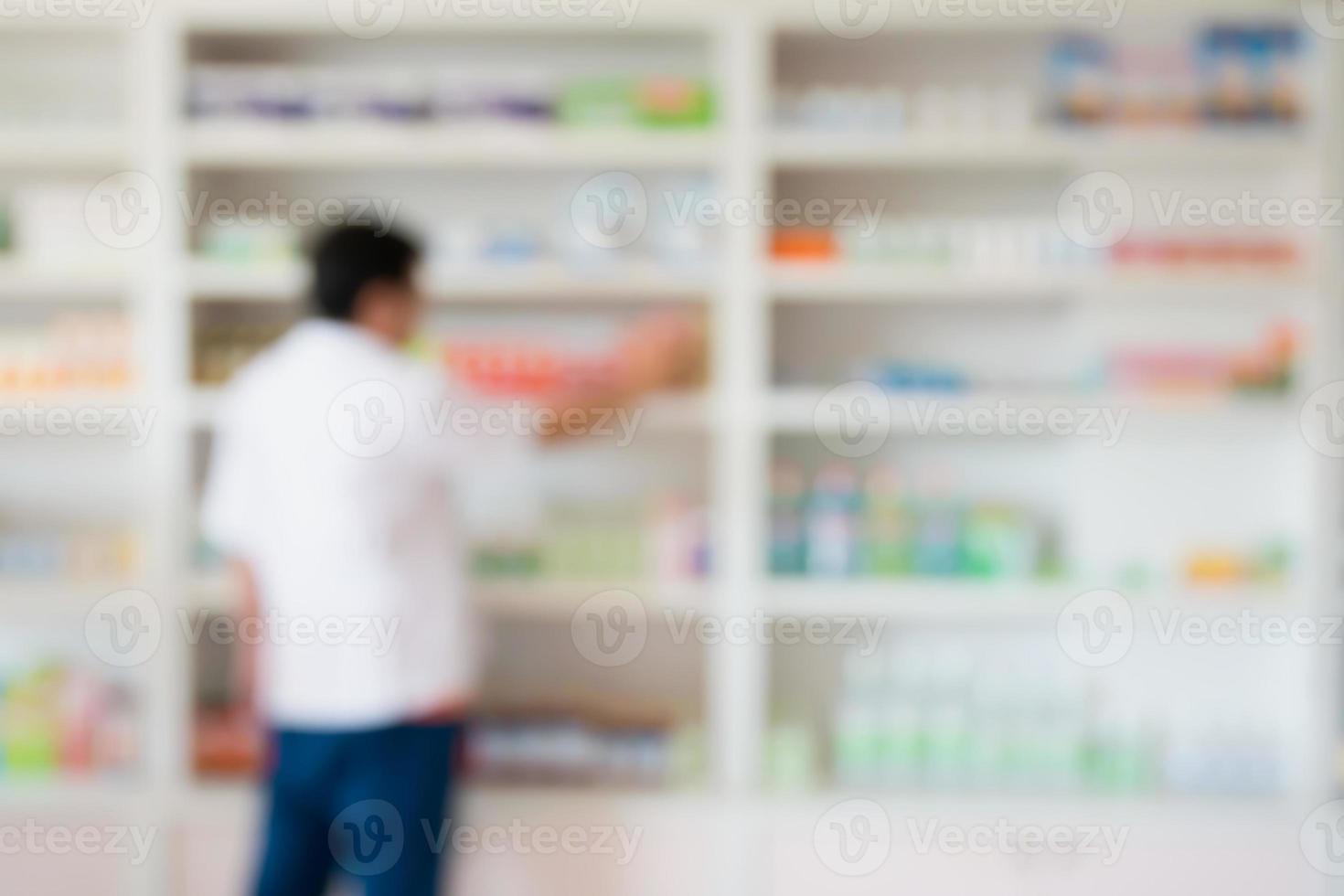 blur pharmacist taking medicine from shelf in the pharmacy photo
