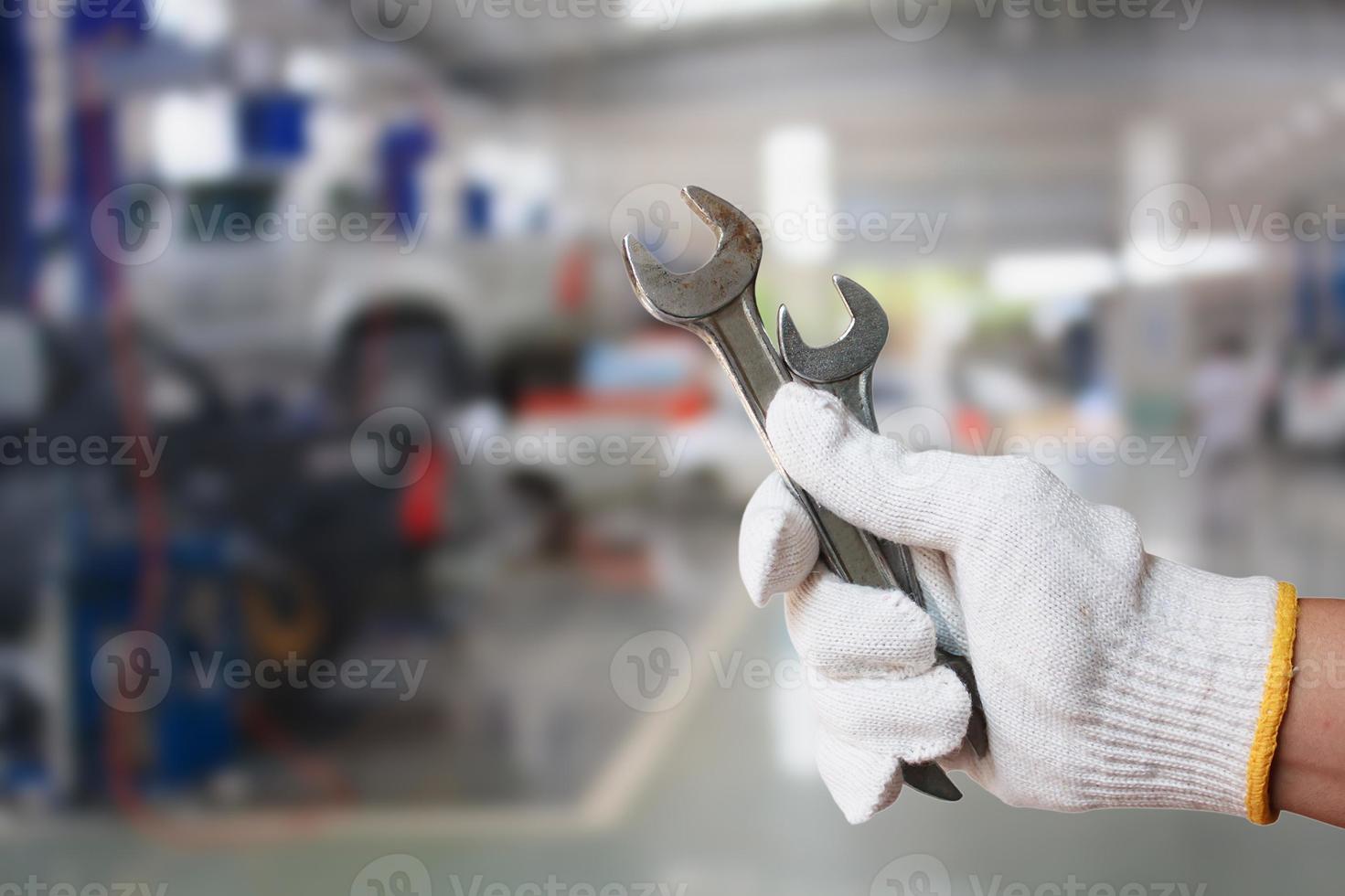 Technician holding a wrench with car repair service center background photo