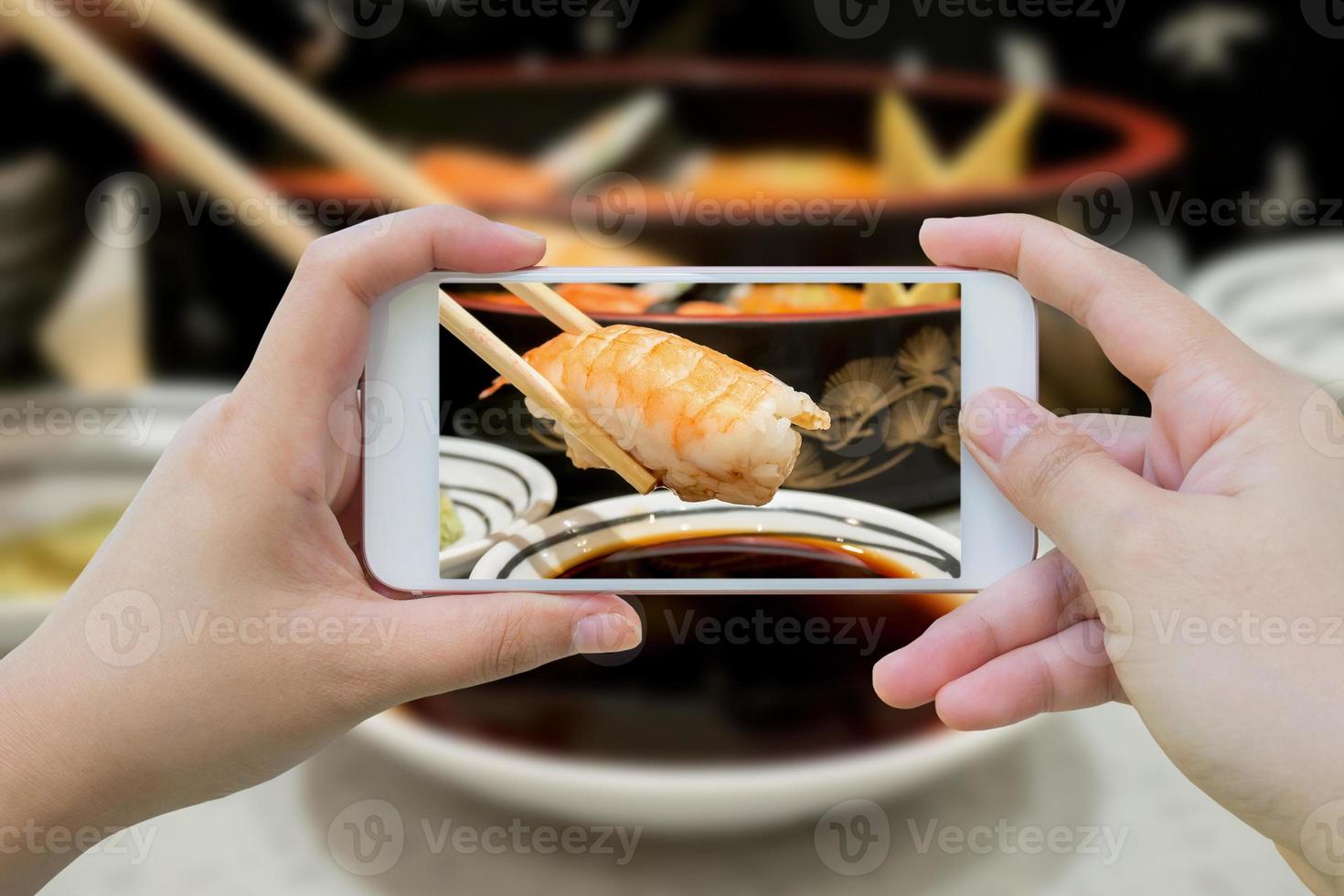 Taking photo of prawn sushi in chopsticks