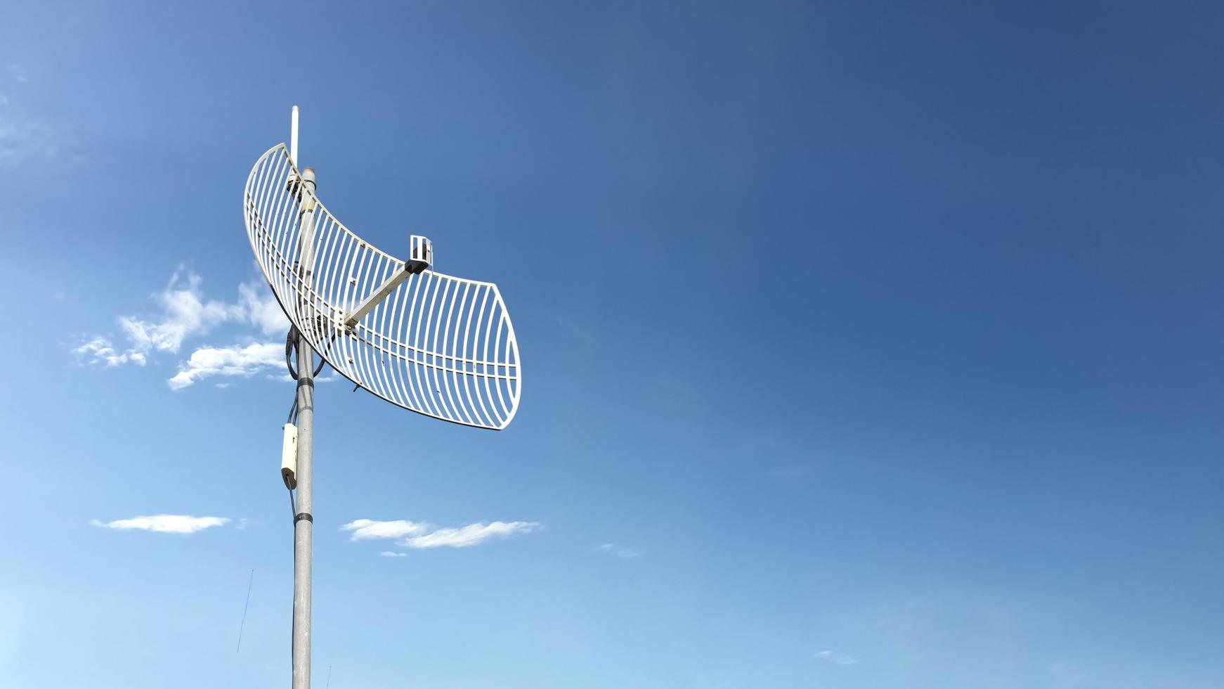 receptor wifi de Internet al aire libre y antena repetidora en el techo del edificio con un fondo azul claro. foto