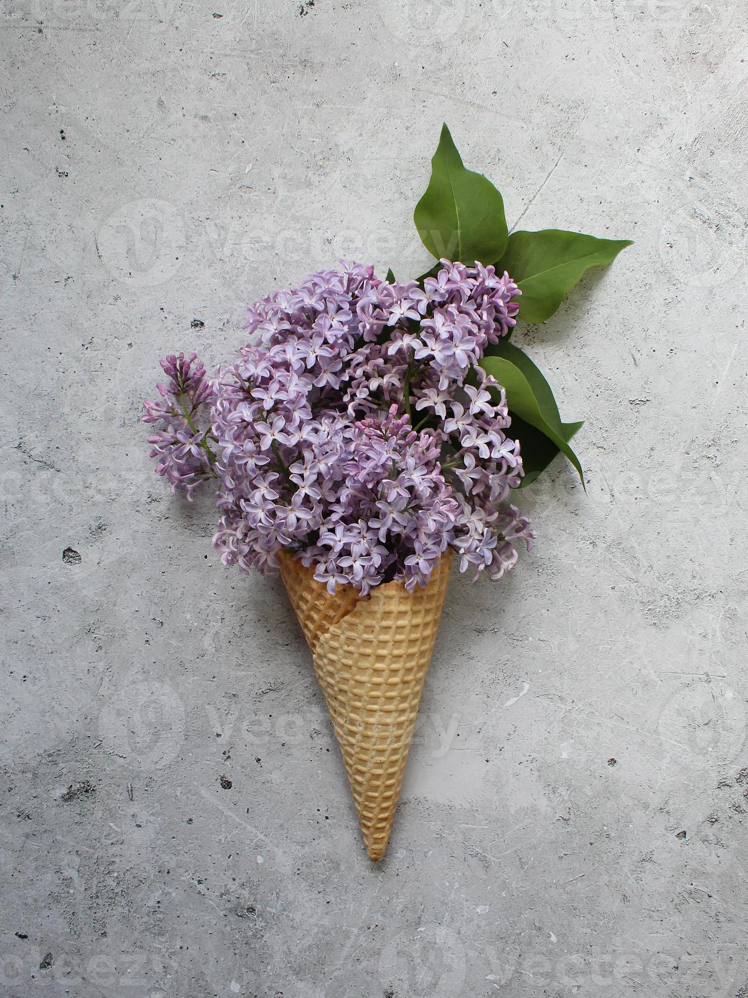 Ice cream cone with colorful flowers on grey background. Flat lay