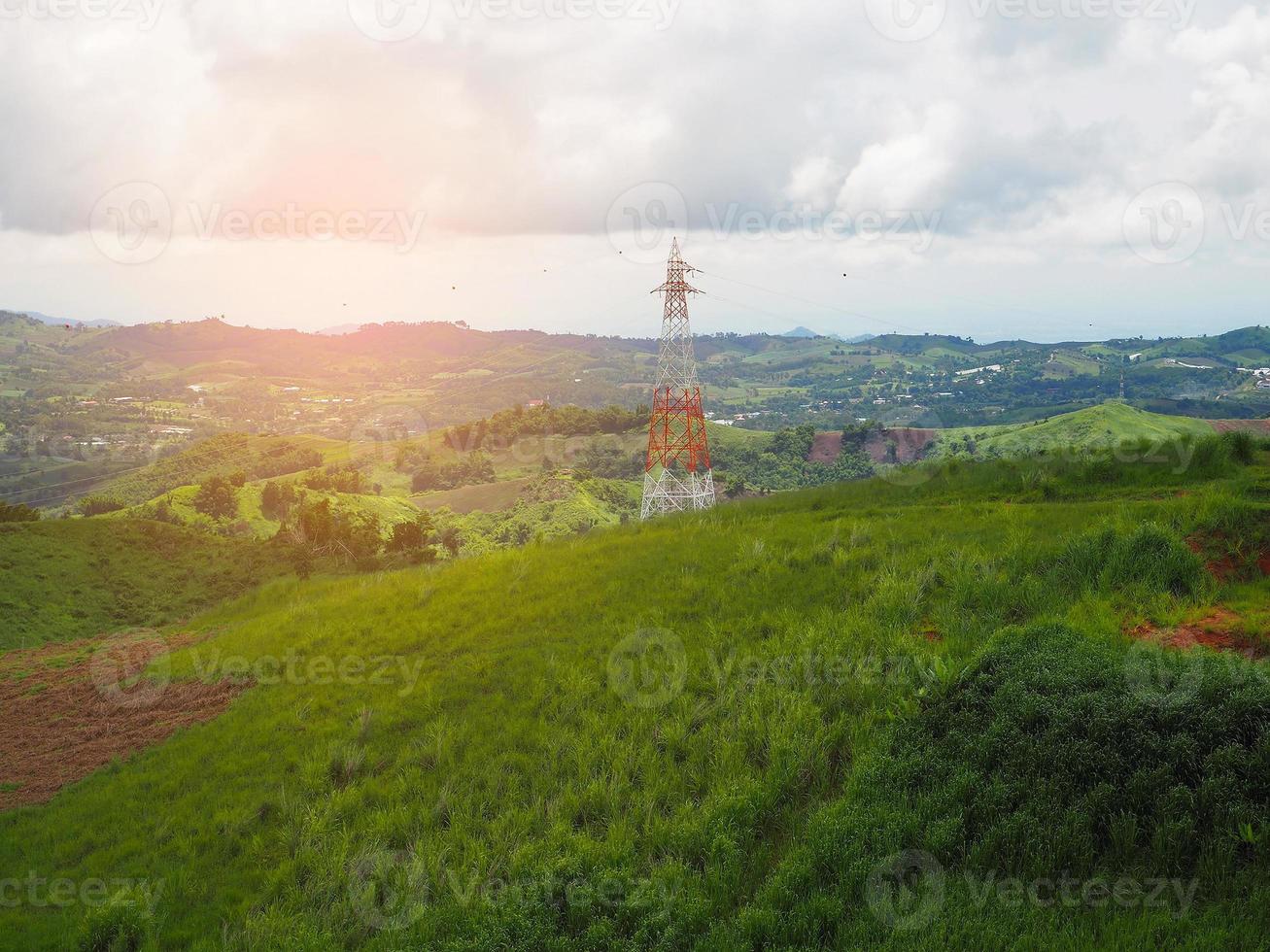 High voltage power lines tower on green mountain photo