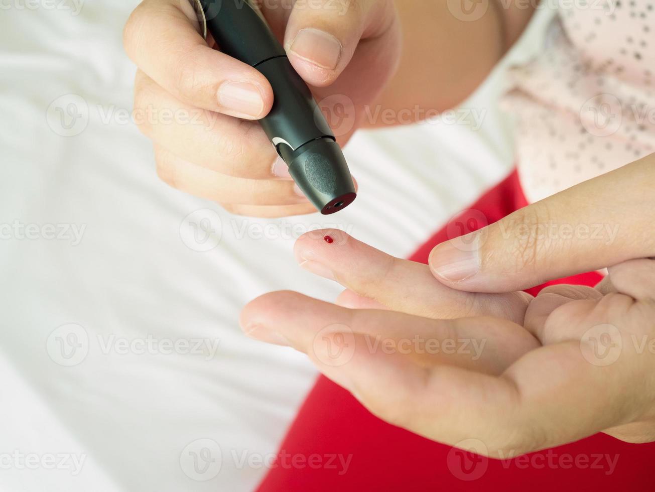 mujer usando lanceta en el dedo, prueba de diabetes foto