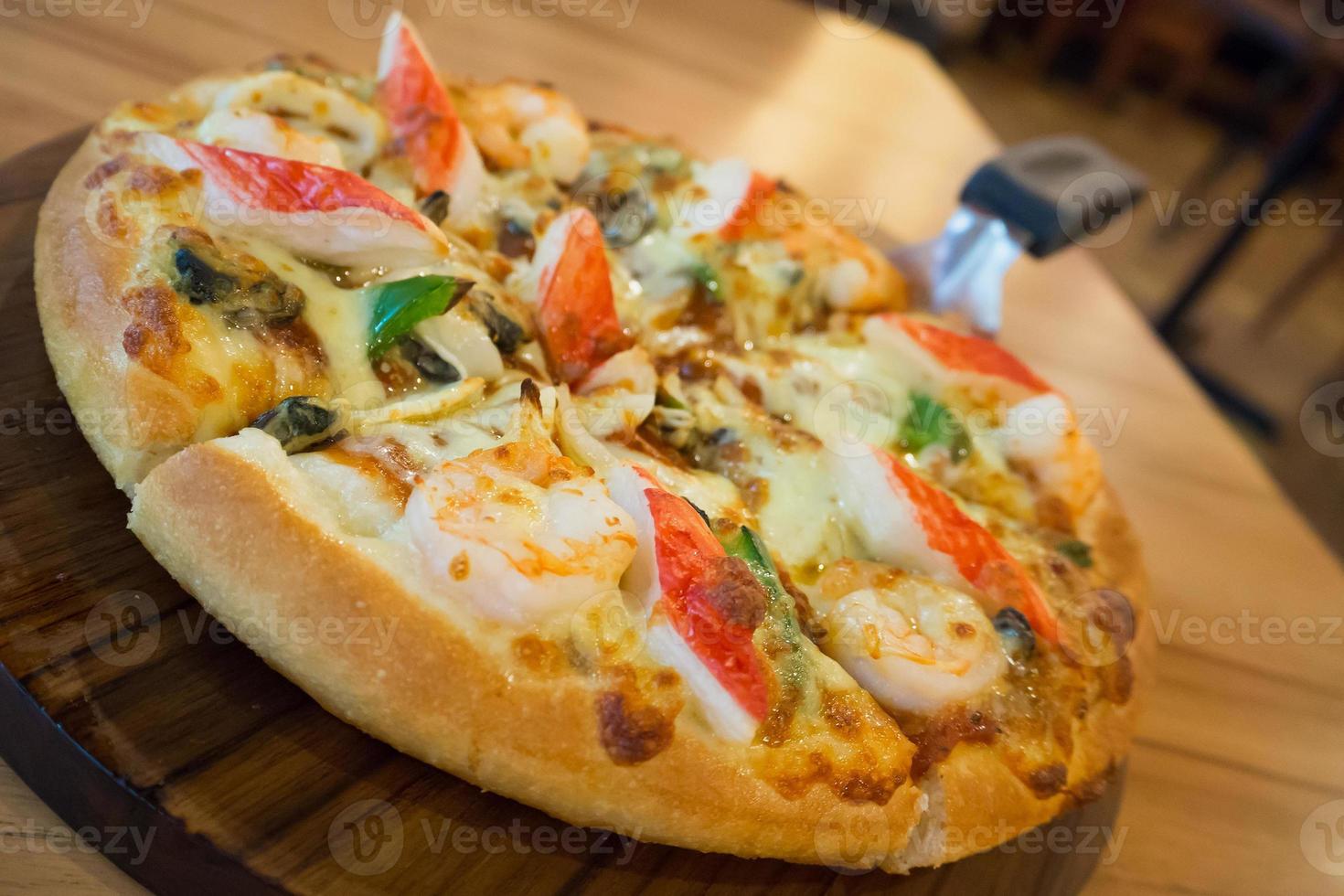 Delicious seafood pizza on wooden table photo