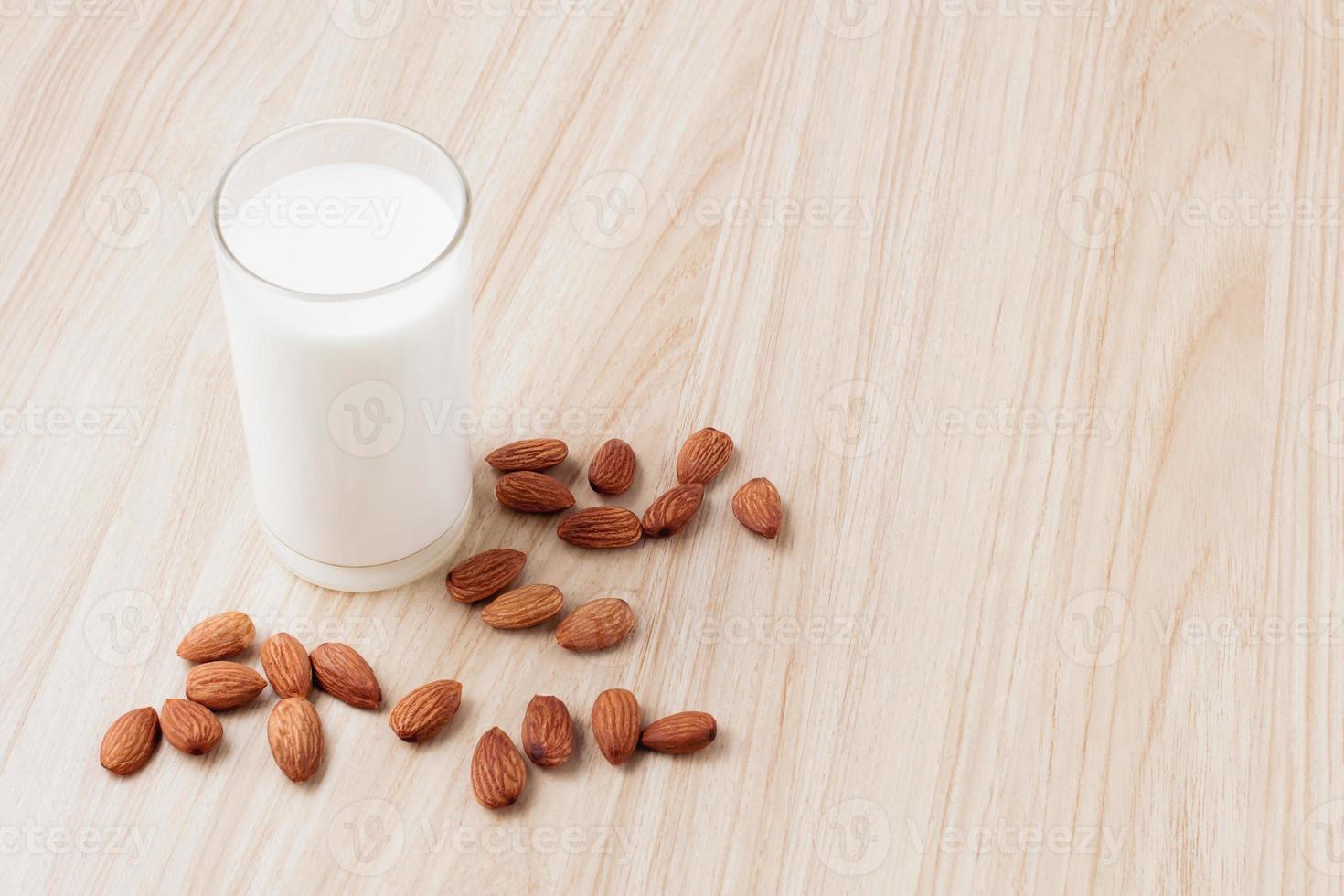 almond milk in glass with nuts around on wood background.selective focus.front view.copy space. photo