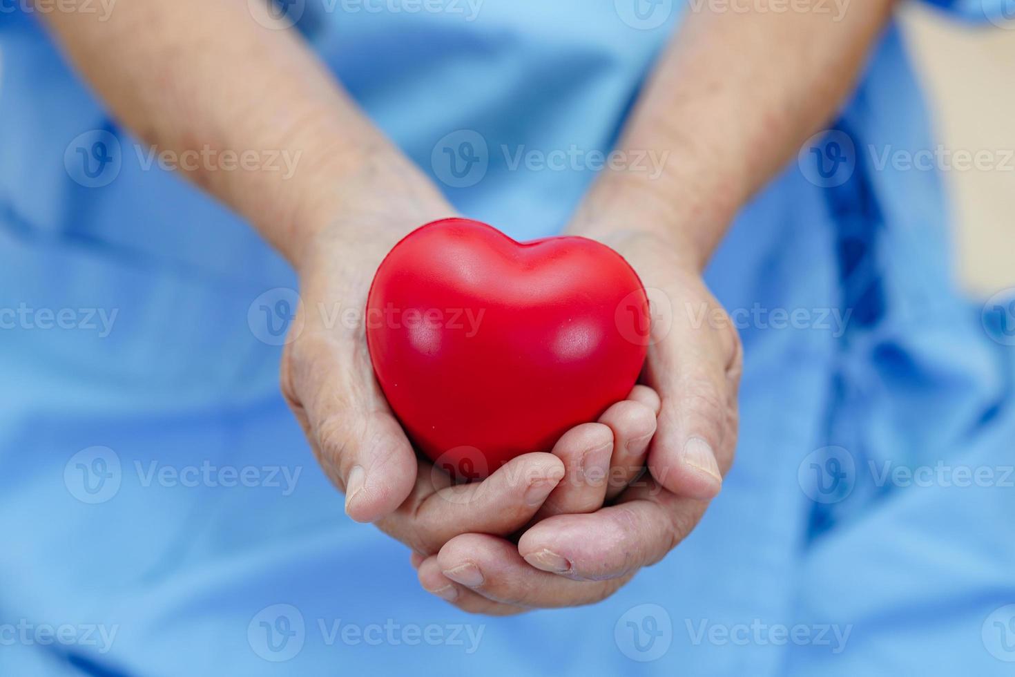 Asian elder senior woman patient holding red heart in hospital. photo