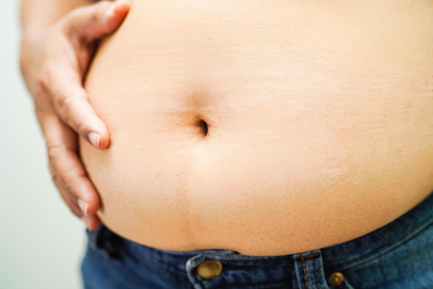 la mujer asiática muestra un vientre gordo de gran tamaño con sobrepeso y obesidad en la oficina. foto