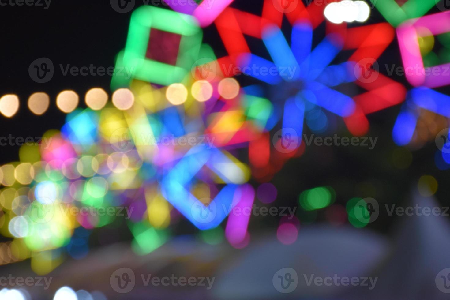 luces nocturnas y bokeh del paseo del parque de diversiones foto