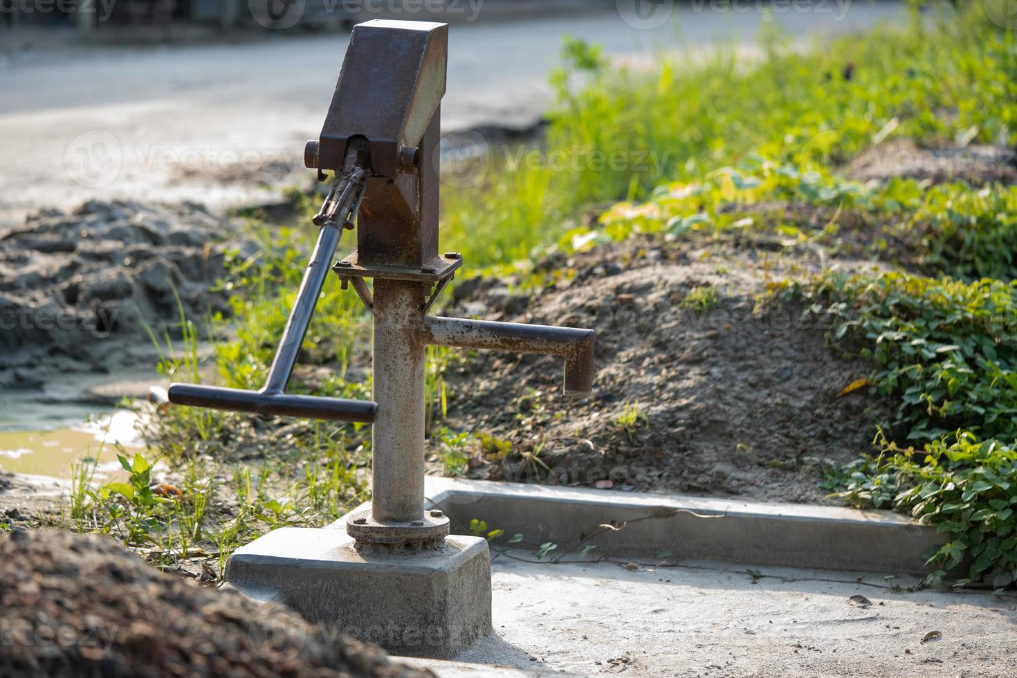 Old hand-operated water pump standing on roadside in the photo