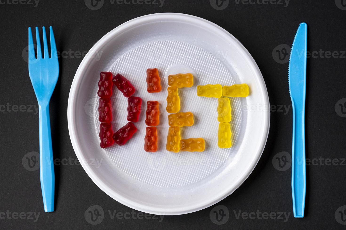 White plastic plate with text DIET from sweet jelly. Sweet fruit gummy bears. Healthy eating, junk food, diet and slimming concept, top view. photo