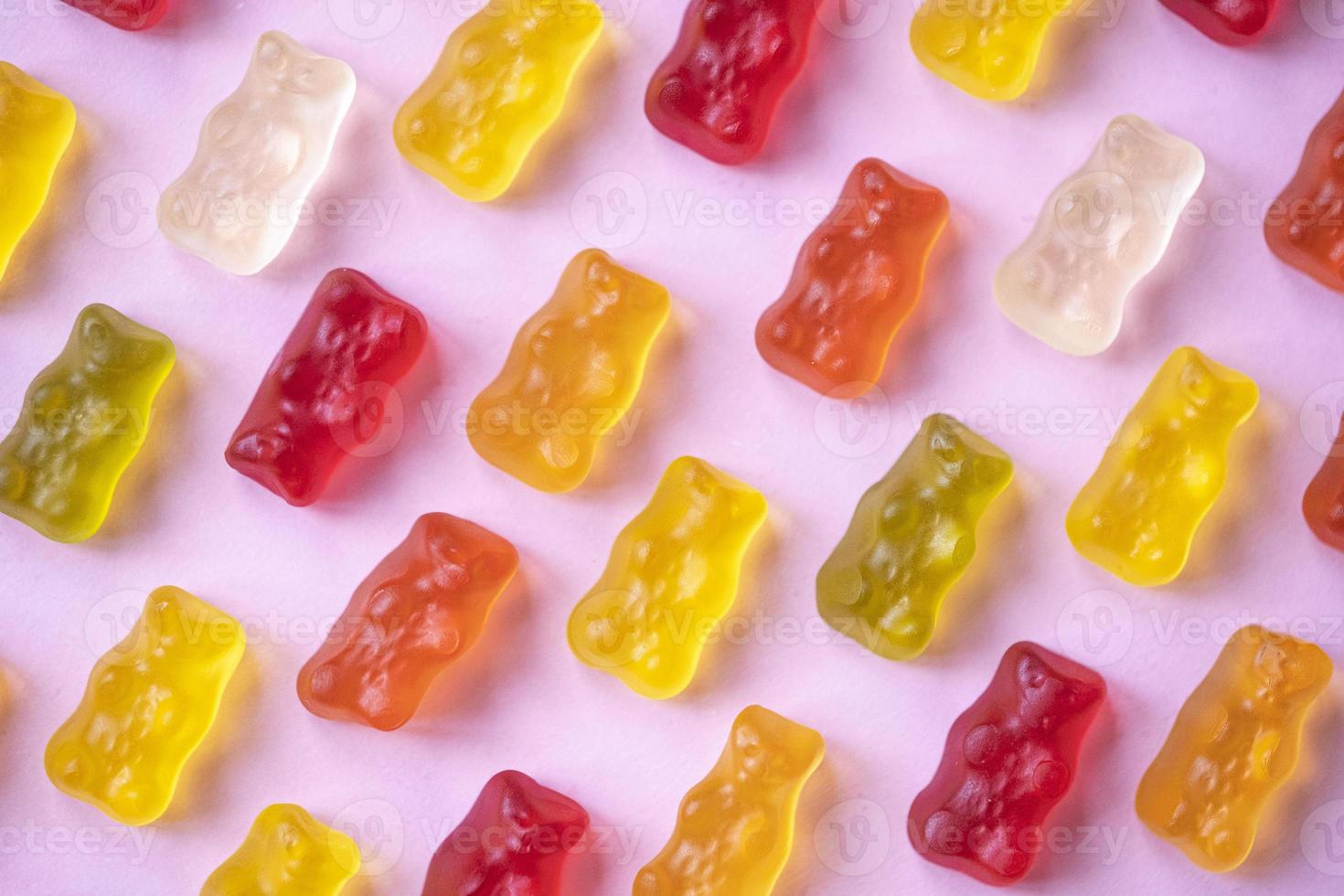 Sweet fruit gummy bears on pink background. Orange, red and yellow marmalade bears. Candy colorful pattern. Minimal design, flat lay, top view. photo