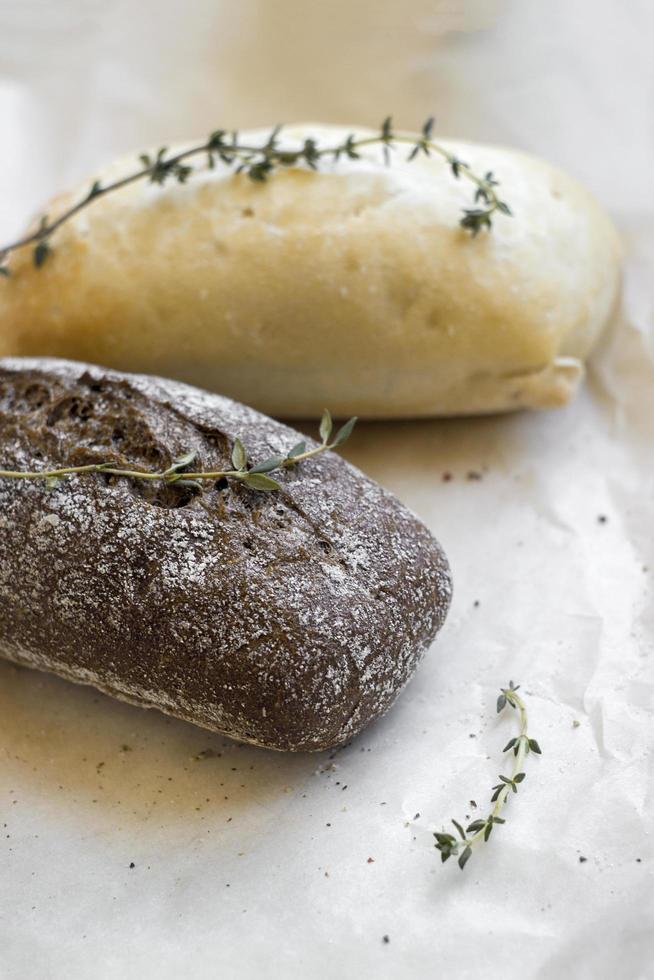 French baguettes with thyme on kraft paper. Mini baguette bread. Top view food, close up photo