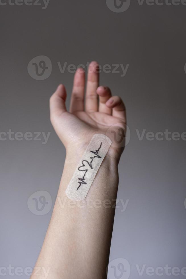 Female hand with band-aid and drawing pulse on black background. Love, loneliness or help concept. Minimal style photo