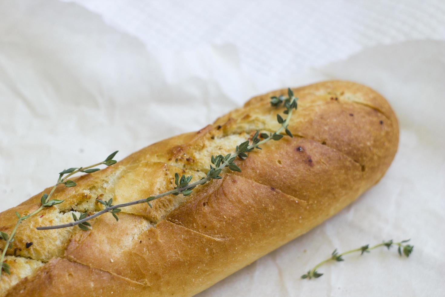 baguettes francesas con tomillo sobre papel kraft. mini pan baguette. vista superior comida, primer plano foto