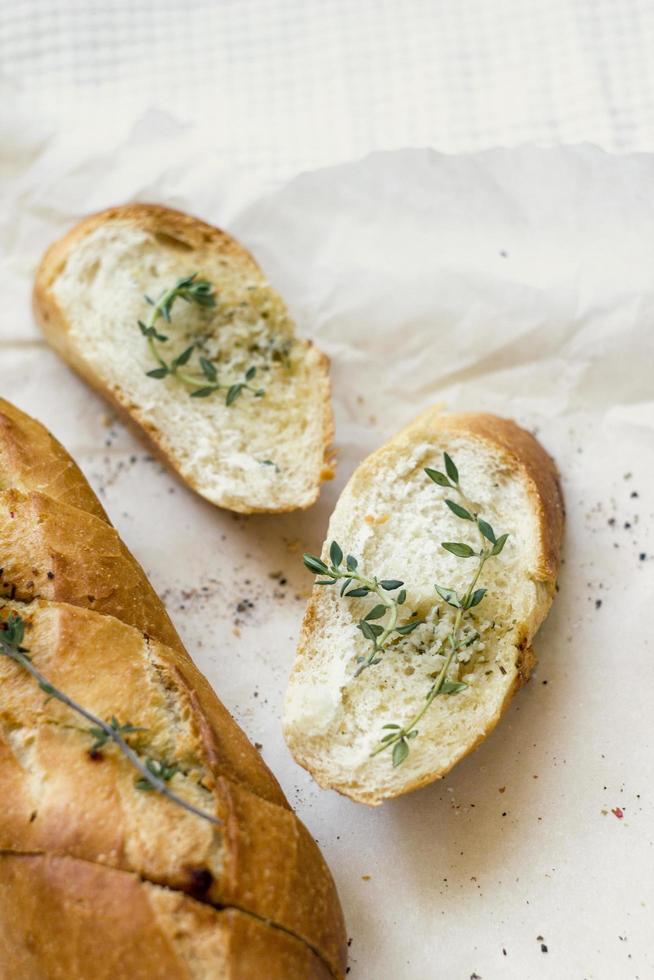 French baguettes and cut slice with thyme on kraft paper. Top view food, close up photo