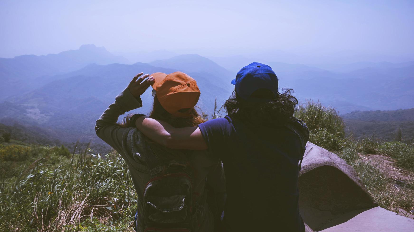 Lover women and men asians travel relax in the holiday. Sit and watch landscape on the Moutain. Mountain Park happily. In Thailand photo