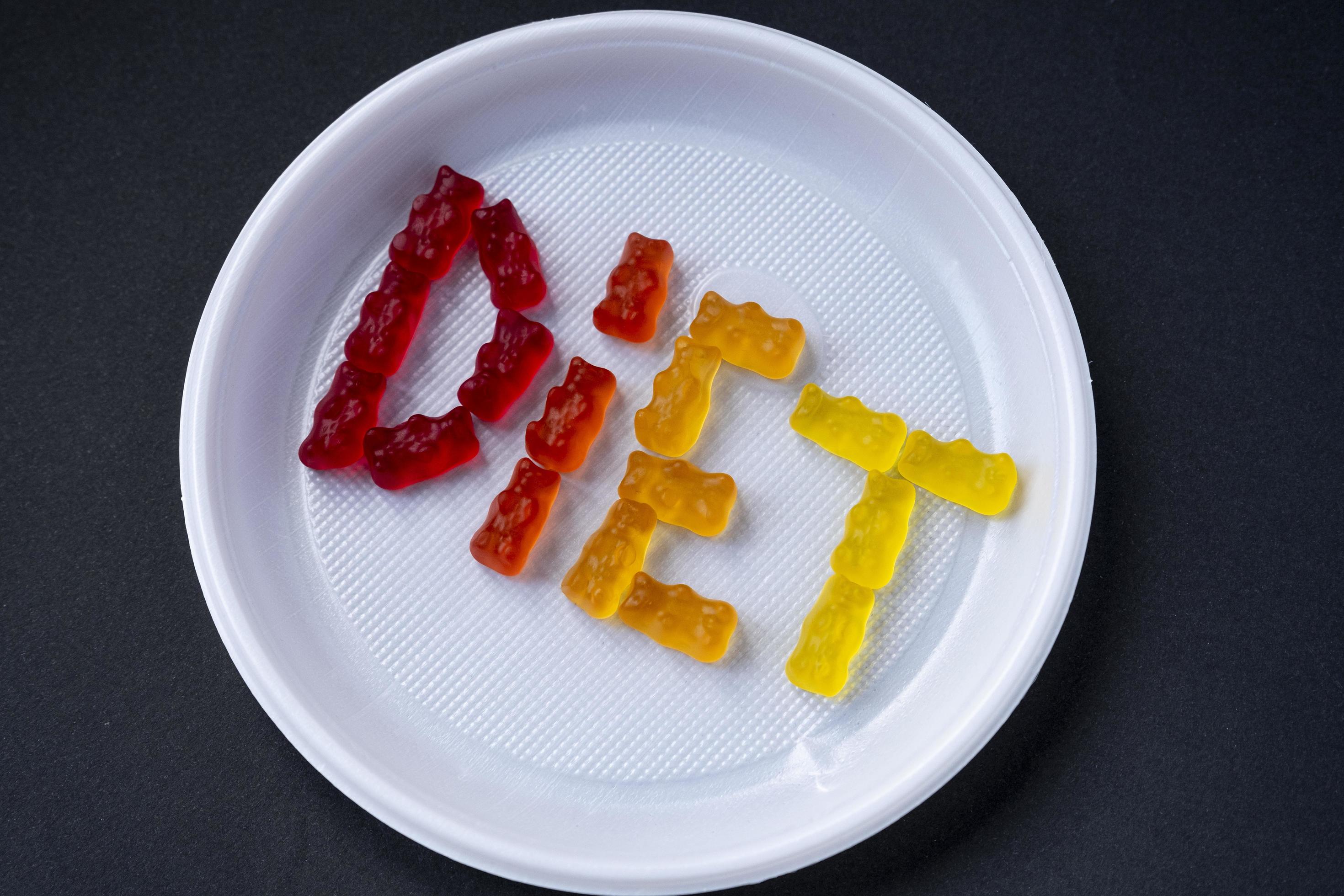 White plastic plate with text DIET from sweet jelly. Sweet fruit gummy