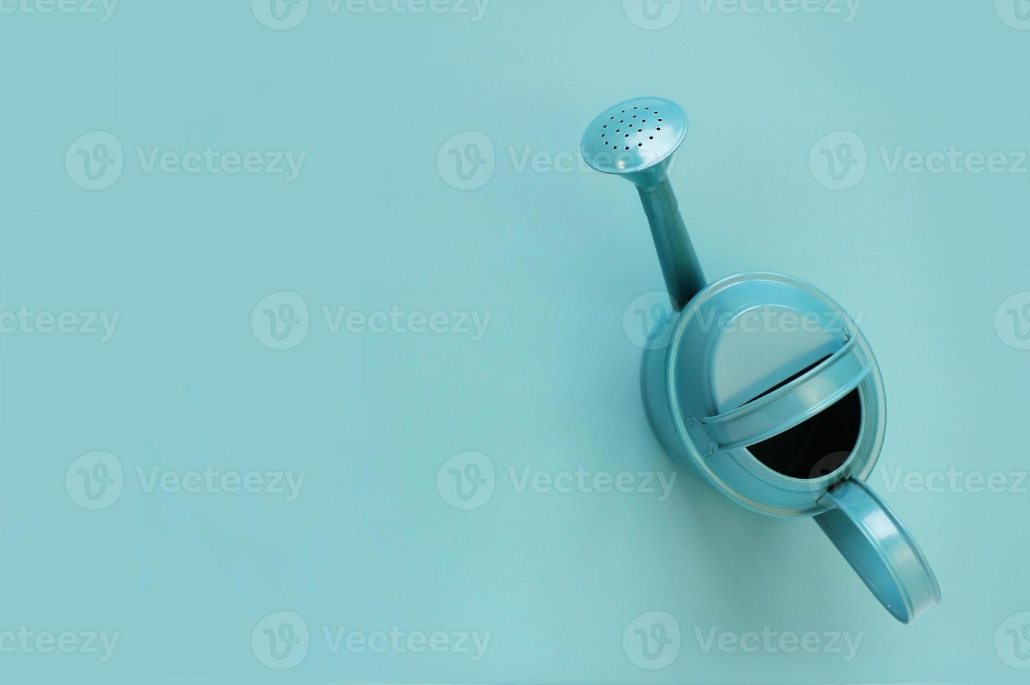 blue watering can on blue background. Creative concept of investment, growth, success in business and life or hello summer. Top view Flat lay photo
