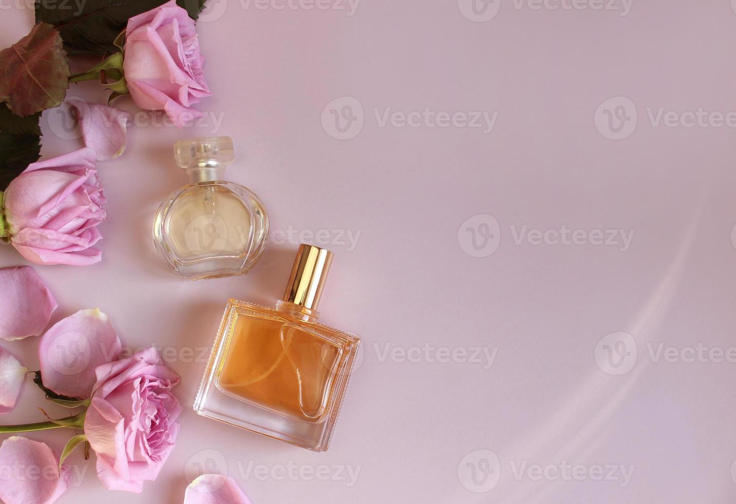 Flat lay composition with elegant perfumes on pink background photo