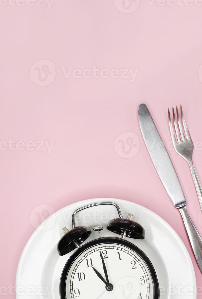 Concept of intermittent fasting, ketogenic diet, weight loss. fork and knife, alarmclock on plate photo
