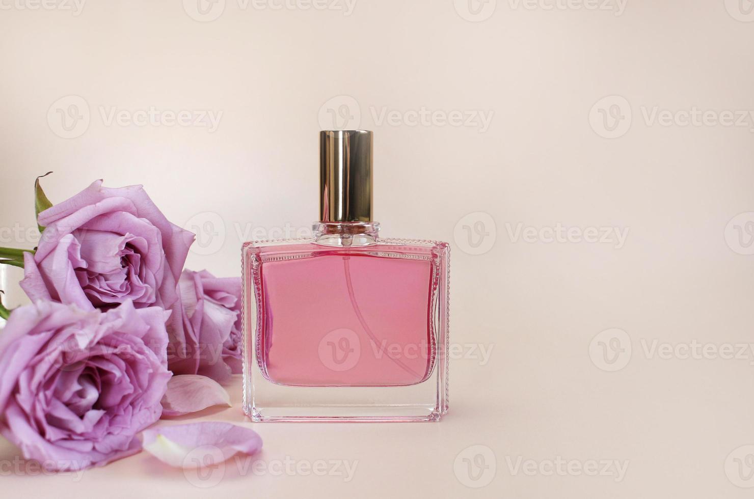 Beautiful composition with perfume and flowers. Perfume bottles, rose flowers petals green leaves on pink background top view Flat lay copy space. Perfumery cosmetics toilet water fragrance collection photo