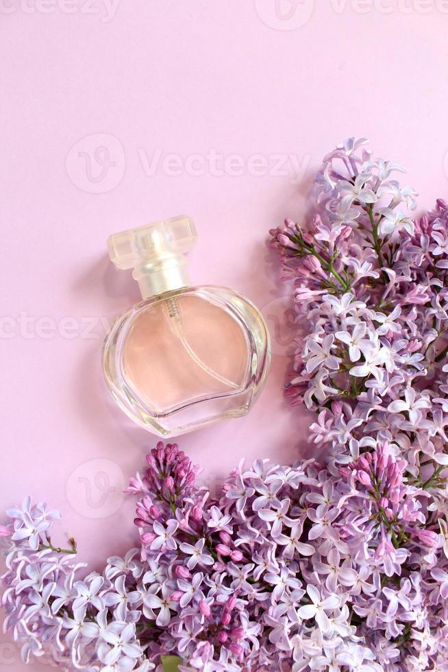 botella de perfume lila con spray de flores lilas en el fondo. composición floral creativa. de cerca. concepto de perfumería natural y aroma floral. fragancia fresca de primavera foto