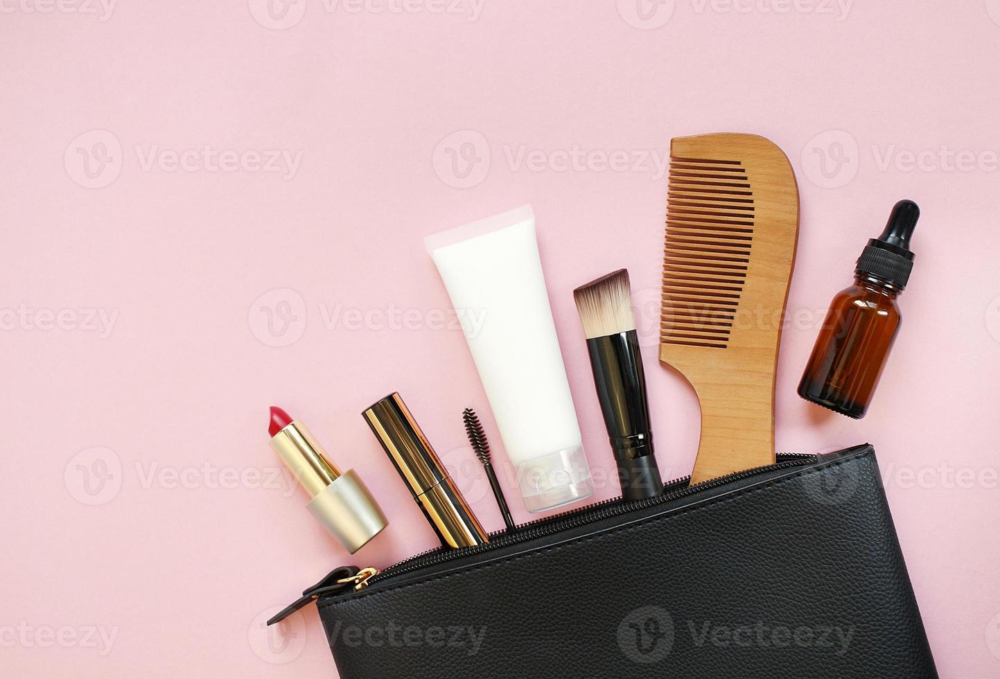 Makeup bag with decorative cosmetics and accessories on pink background