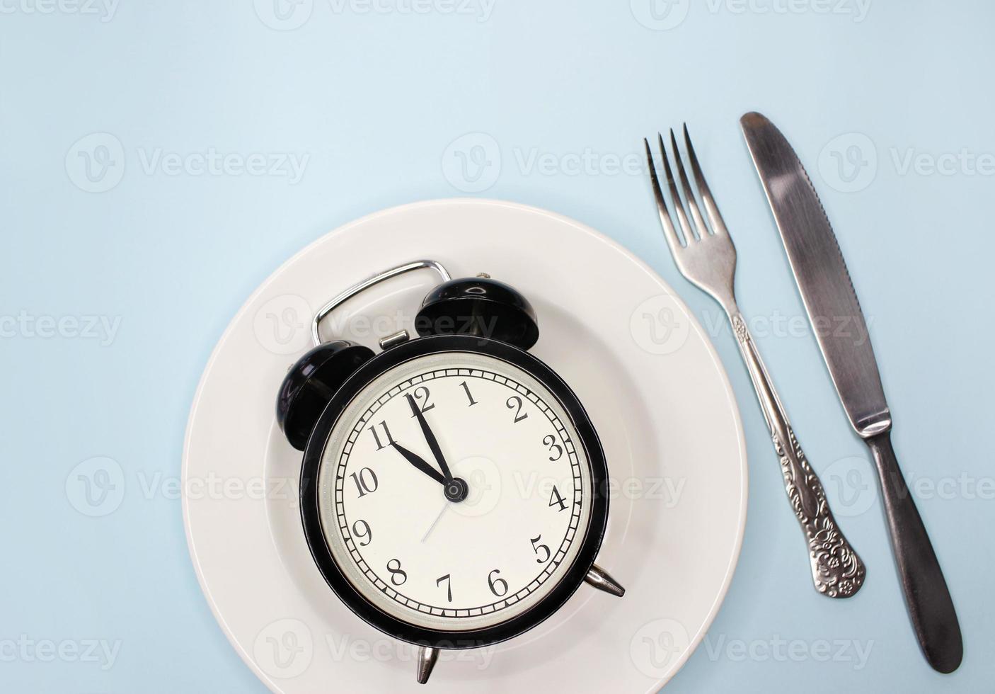 Concept of intermittent fasting, ketogenic diet, weight loss. fork and knife, alarmclock on plate photo