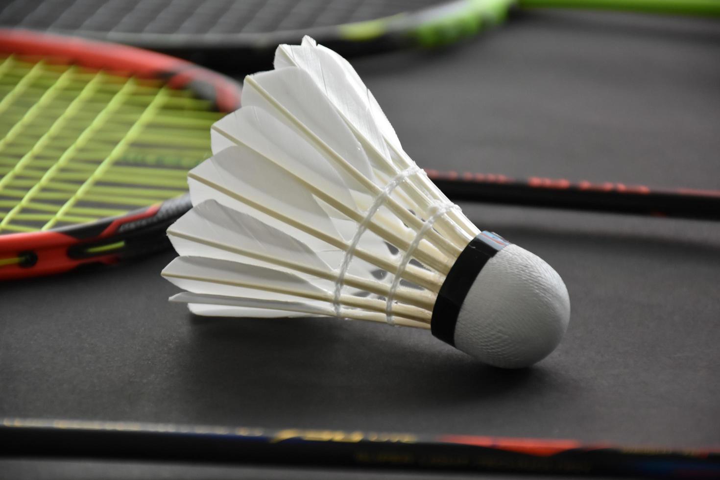 Badminton sports equipments, shuttlecocks, racket, grip, on floor of indoor badminton court. photo