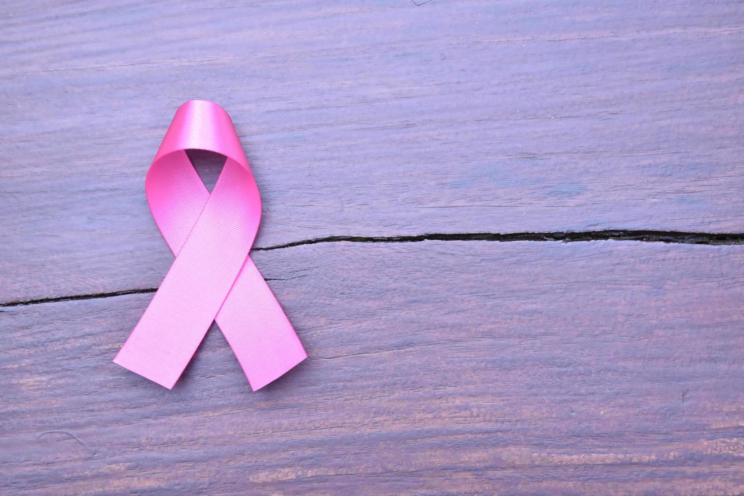 Pink ribbon on wooden table, concept for fighting against breast cancer in woman around the world. Selective focus and copy space. photo