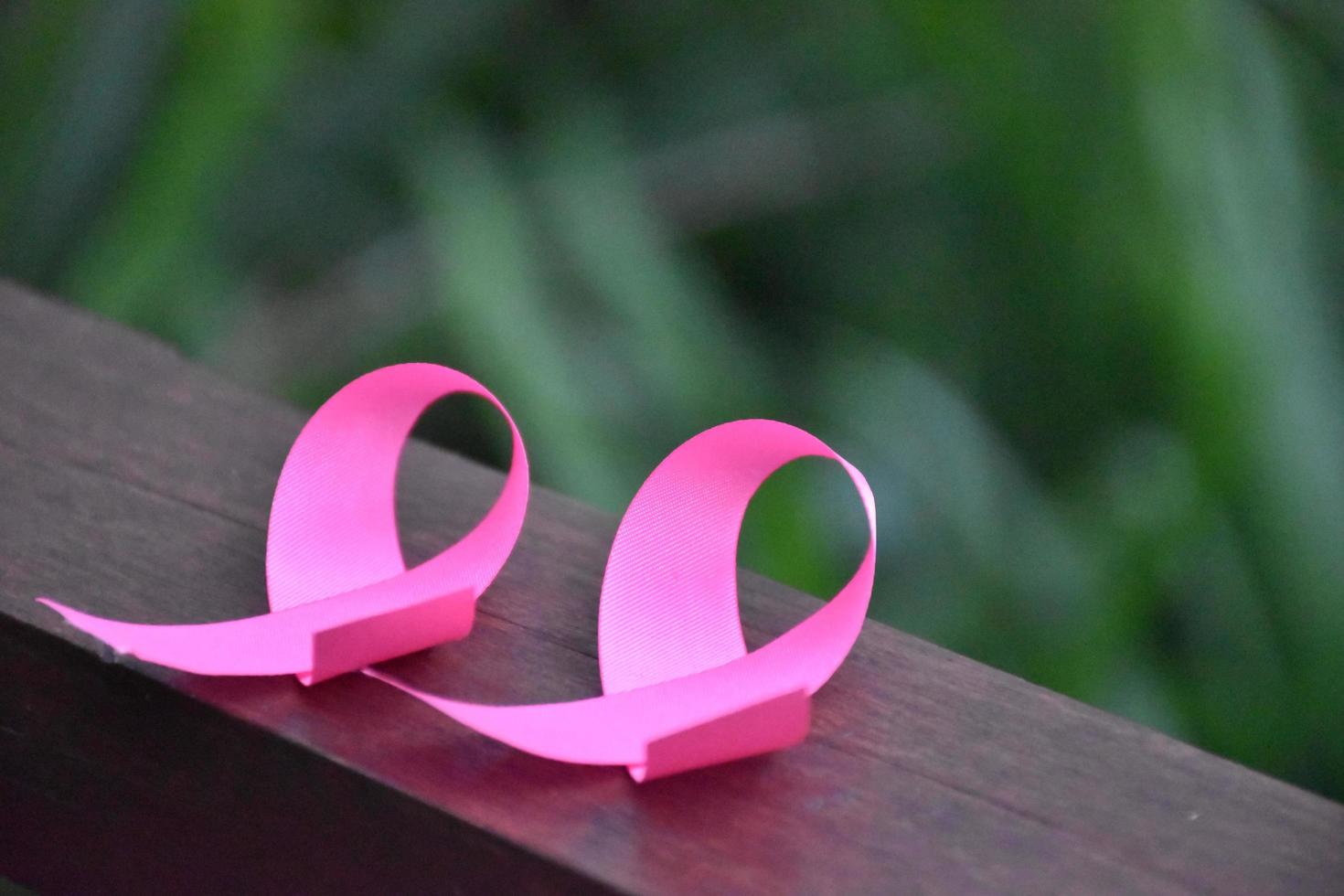 Pink ribbon on wooden table, concept for fighting against breast cancer in woman around the world. Selective focus and copy space. photo