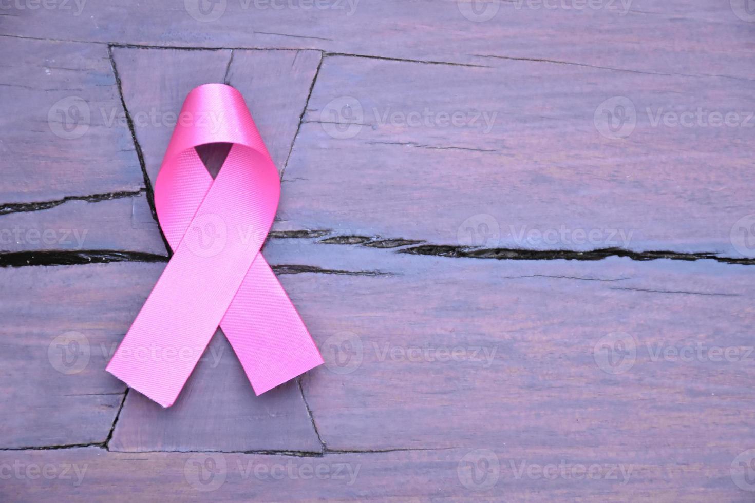 Pink ribbon on wooden table, concept for fighting against breast cancer in woman around the world. Selective focus and copy space. photo