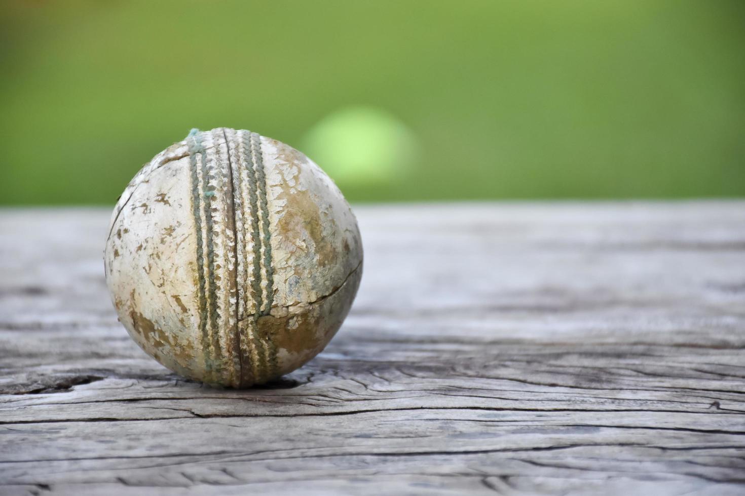 antiguos equipos deportivos de cricket de entrenamiento en suelo oscuro, pelota de cuero, wickets, casco y bate de madera, enfoque suave y selectivo, concepto tradicional de amantes del deporte de cricket en todo el mundo. foto