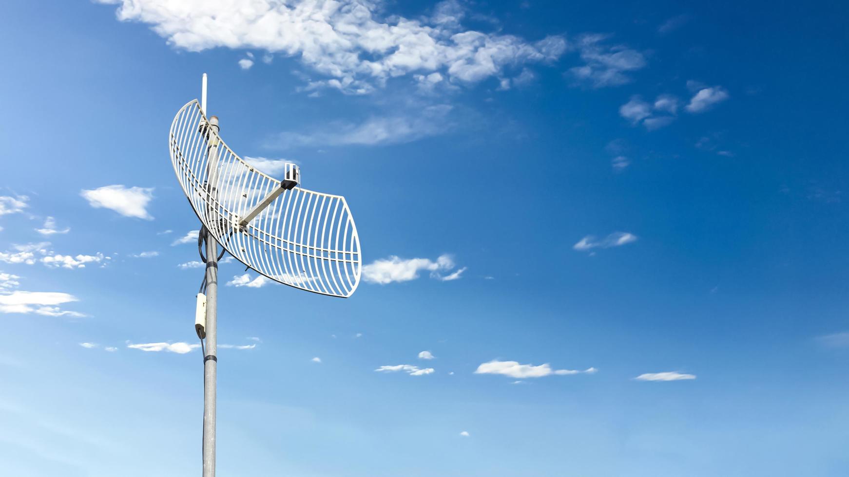 receptor wifi de Internet al aire libre y antena repetidora en el techo del edificio con un fondo azul claro. foto