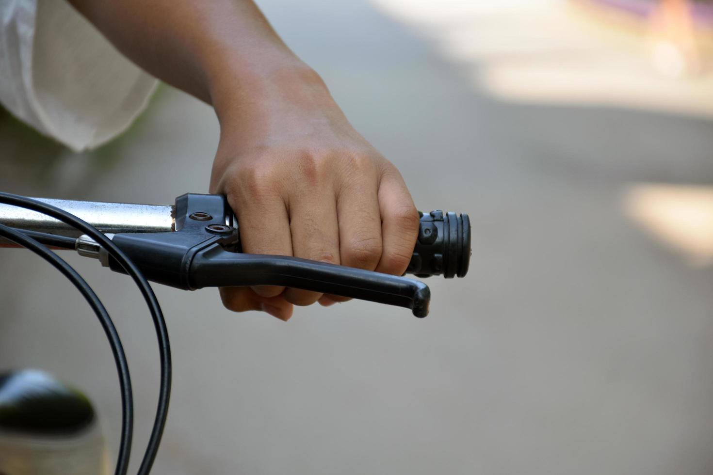 Closeup view of handlebar of bicycle which has hand of kid holding it. photo