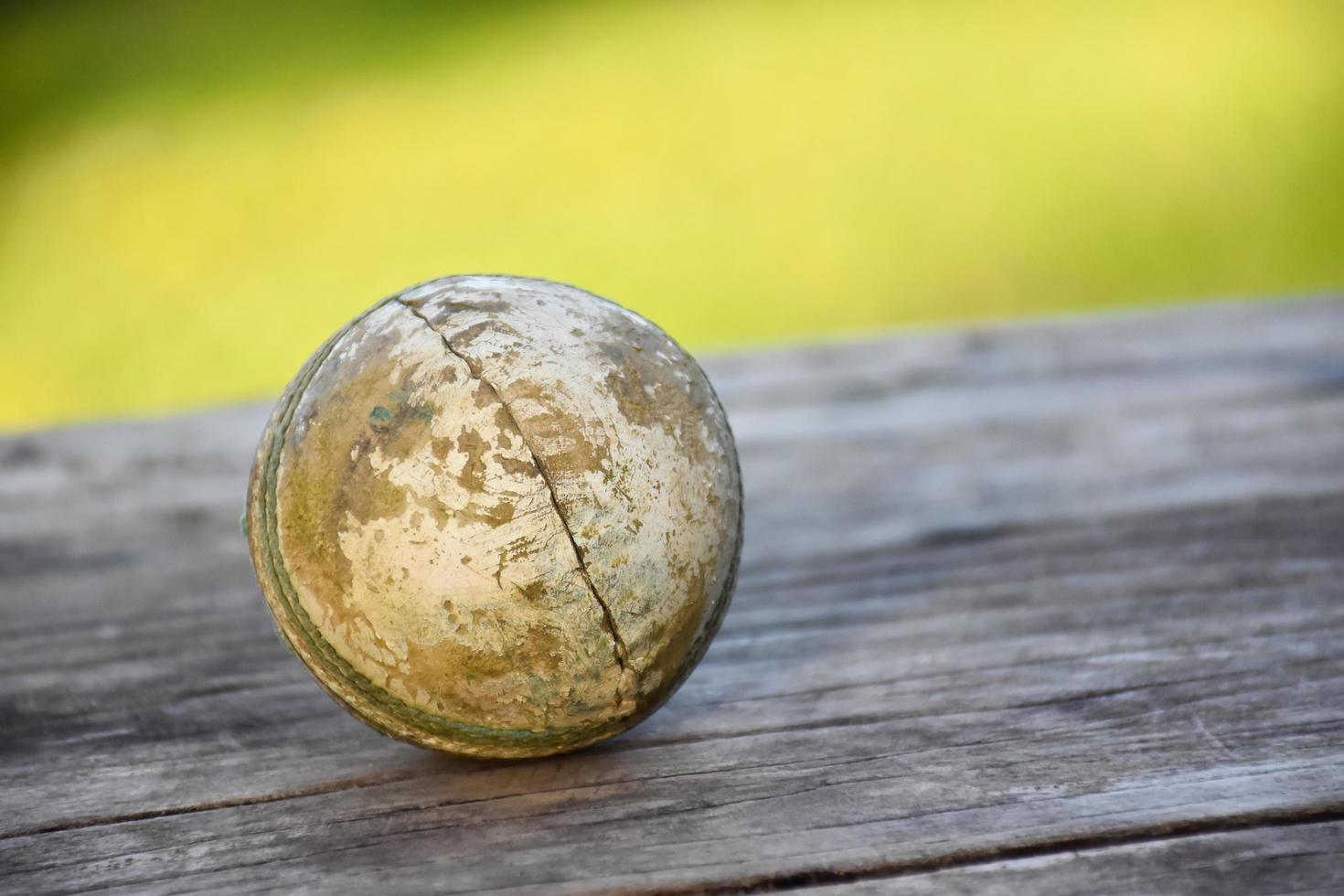 Old training cricket sport equipments on dark floor, leather ball, wickets, helmet and wooden bat, soft and selective focus, traditional cricket sport lovers around the world concept. photo