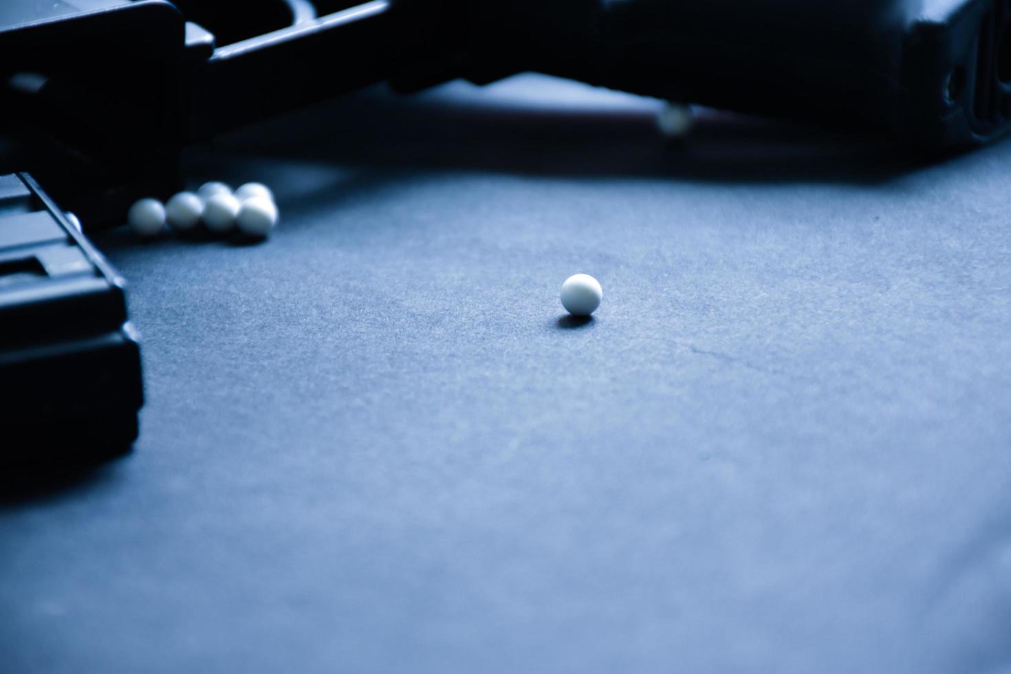 Closeup of white plastic bullets of airsoft gun or bb gun on wooden floor, soft and selective focus on white bullets. photo