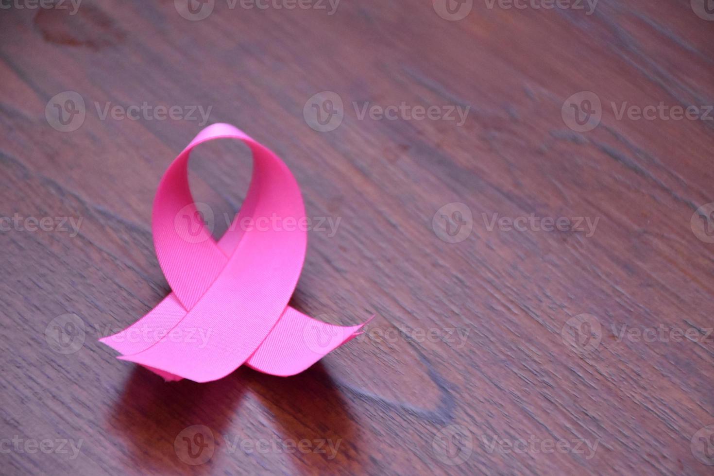 Pink ribbon on wooden table, concept for fighting against breast cancer in woman around the world. Selective focus and copy space. photo