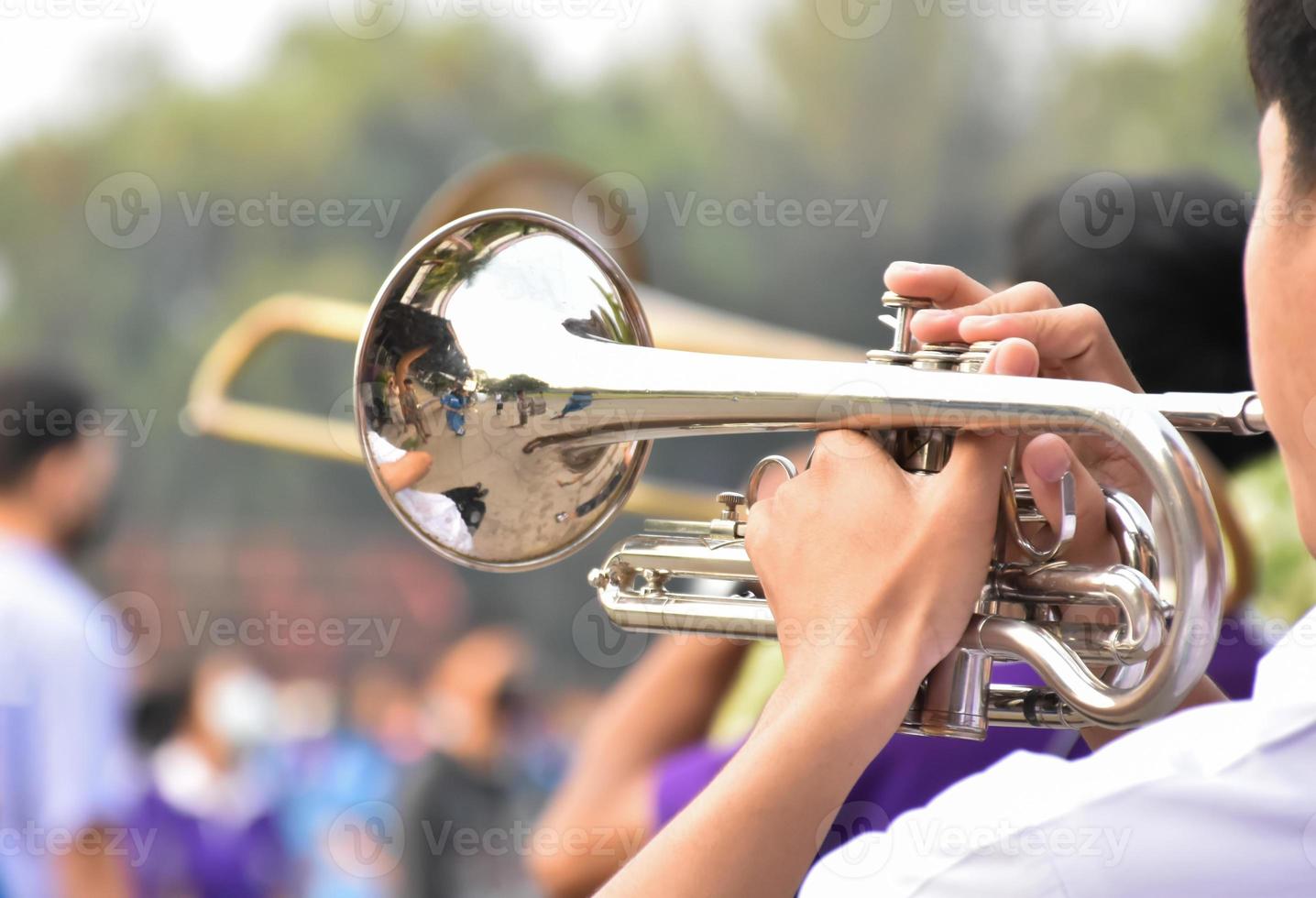 Asian young boy student blowing a trumpet with school marching band, blurred background photo